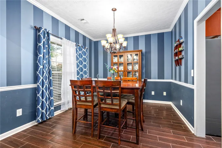 This dining area features rich wood flooring, crown molding, and a charming chandelier.