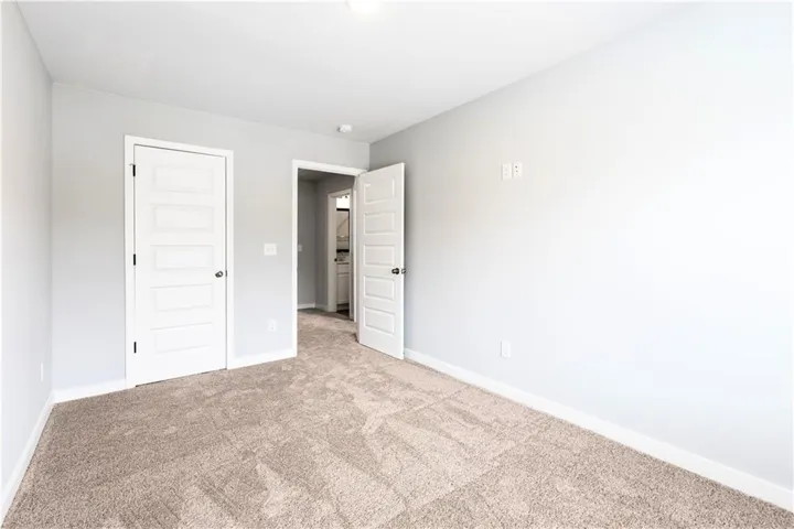 This spacious room offers plush carpeting, clean walls, and inviting doorways.