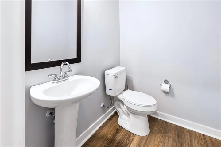 Functional bathroom featuring elegant hardwood flooring and a classic pedestal sink, perfect for everyday use.