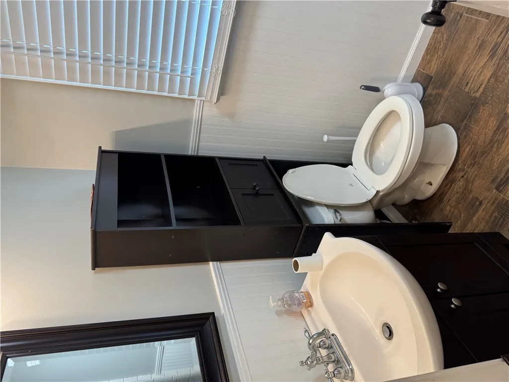 A well-appointed lavatory featuring beadboard wainscoting and warm wood-look flooring.