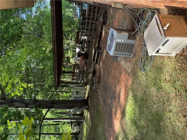 This serene outdoor space features lush greenery and a charming brick pathway leading to a covered patio.