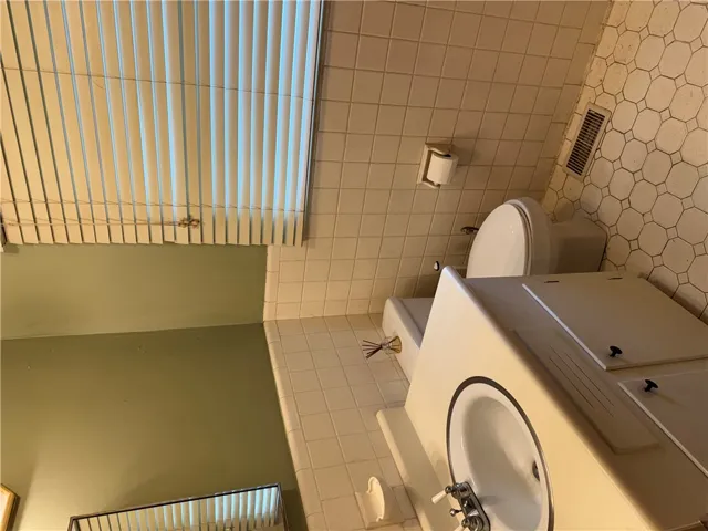 Functional bathroom featuring a well-maintained sink and toilet, complemented by clean tiled surfaces.