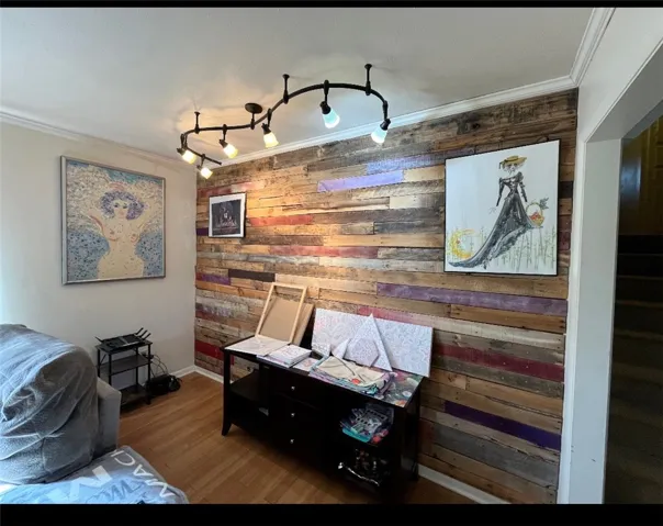 This versatile room features a distinctive wood accent wall and elegant crown molding.
