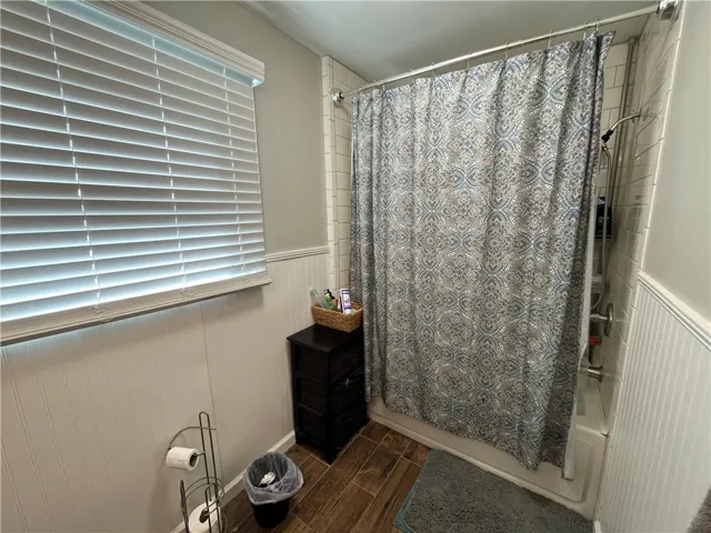This bathroom features wood flooring and a shower-over-tub design.