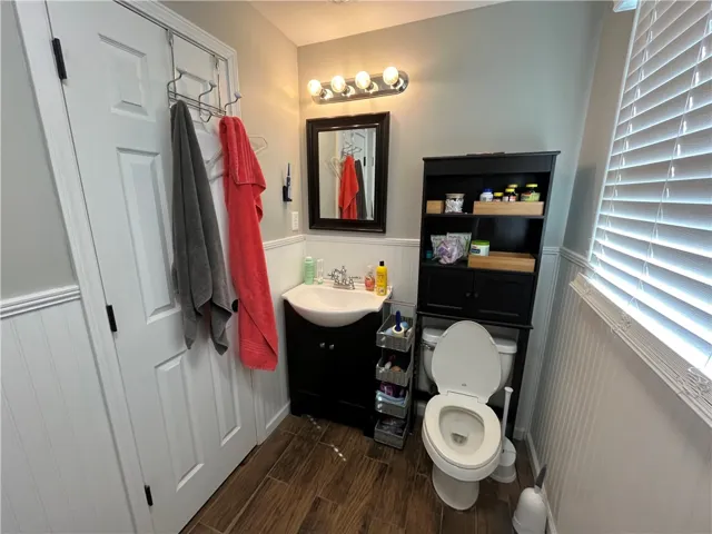 This clean and functional bathroom features wood-look tile flooring and wainscoting.