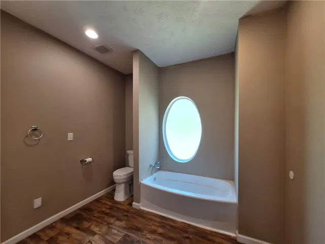 This primary bathroom offers a calming retreat with an oval window and comfortable bathtub.