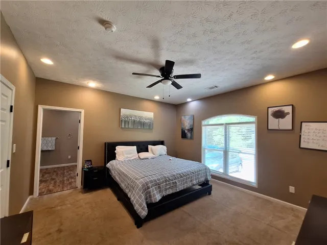 This spacious room features vaulted ceilings, recessed lighting, and a large arched window.