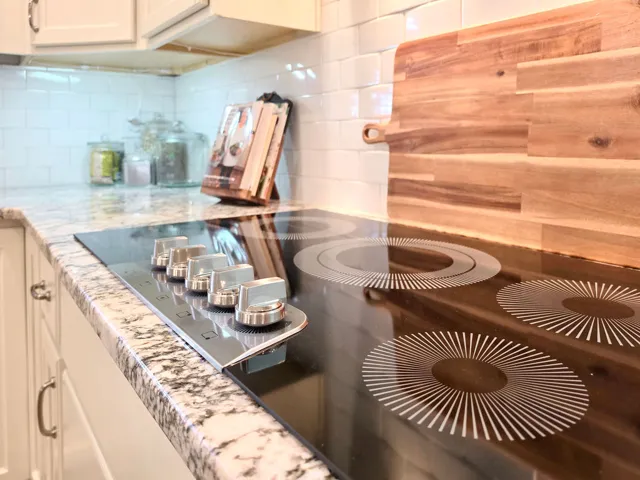 This kitchen showcases a modern electric cooktop integrated into a beautiful granite countertop.