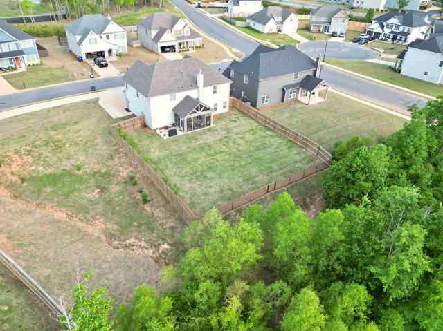 This aerial view showcases a residential property with a private yard and natural surroundings.