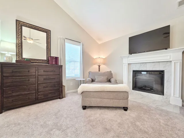 This cozy primary  retreat features an electric fireplace, plush carpet, and ample natural light.