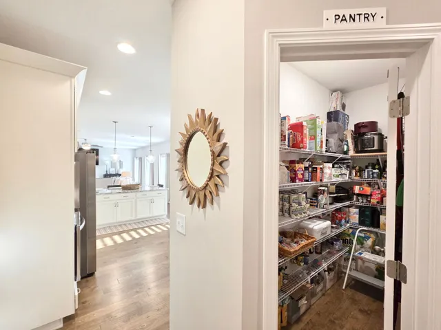 This spacious walk-in pantry provides ample storage, complementing the adjoining kitchen with an island and recessed lighting.