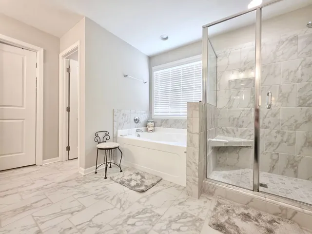 Primary Ensuite Bath features a spacious soaking tub and a sleek glass-enclosed shower.