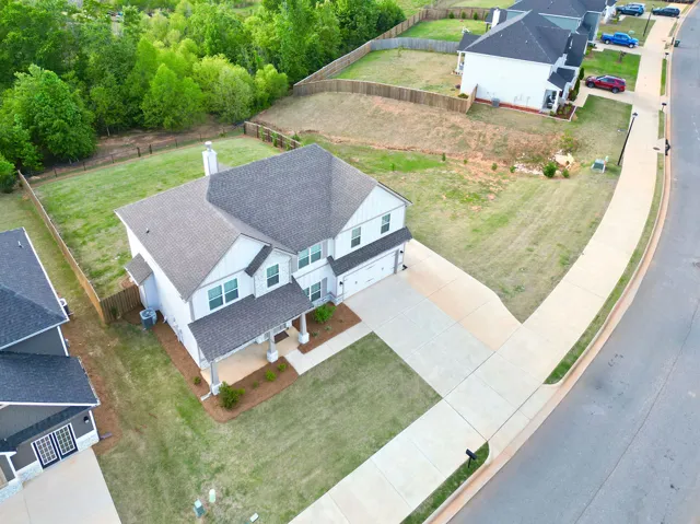 An aerial perspective reveals a contemporary residence with an inviting front porch and a spacious driveway.