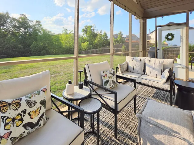 This inviting screened porch offers serene backyard views, perfect for peaceful relaxation.