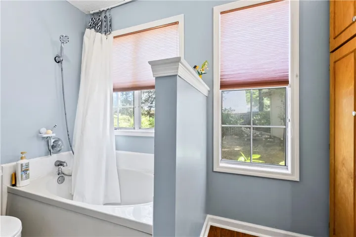 This master bathroom features windows with blinds and a built-in tub with a shower.
