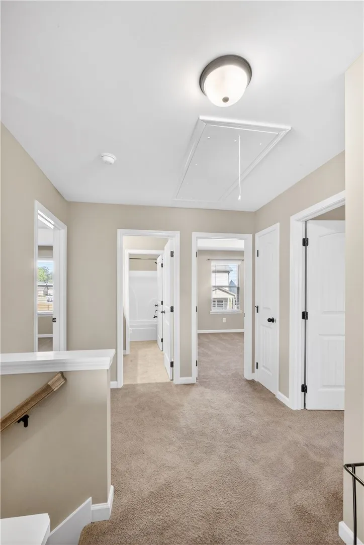 This bright hallway connects multiple rooms with warm, inviting carpet.