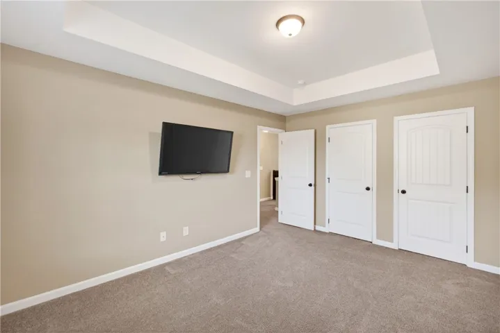 This cozy bedroom offers a tranquil retreat with plush carpeting and elegant tray ceilings.
