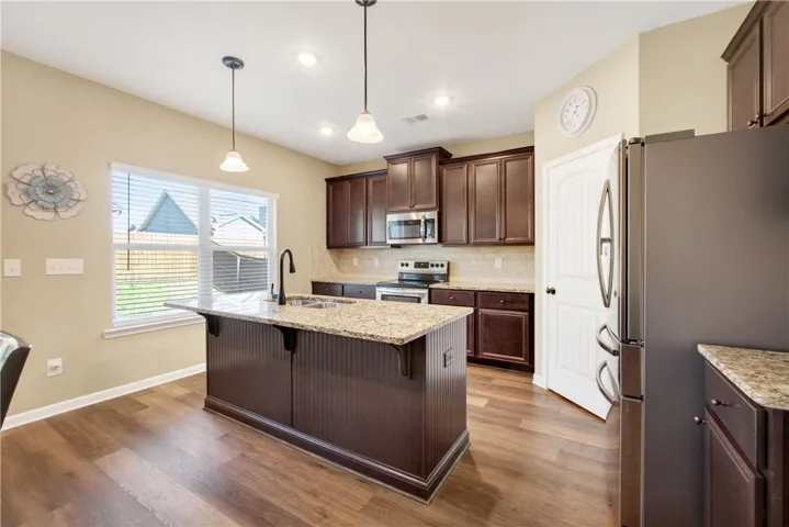 This kitchen features a central island, granite countertops, and rich wood cabinetry.