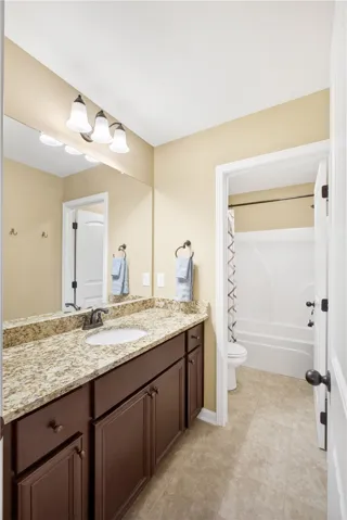 This bright bathroom offers a vanity with ample storage and a shower-tub combination.