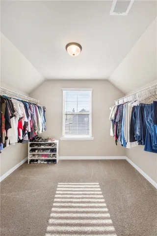 This spacious walk-in closet features ample storage and a window, creating a bright and organized space.