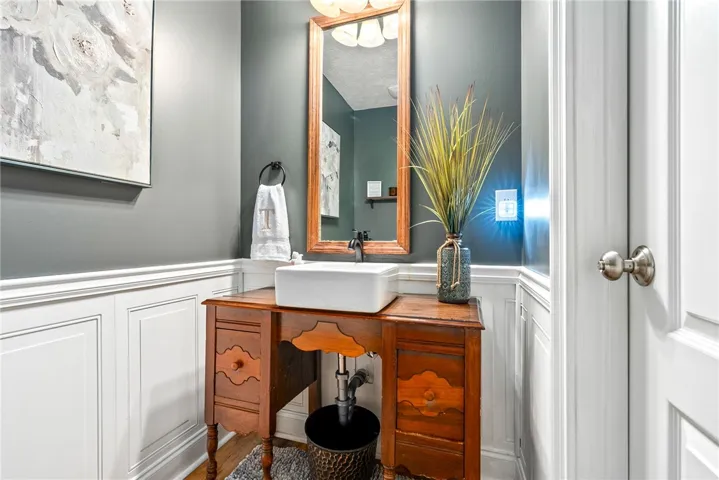 This powder room features a unique wooden vanity and wainscoting.