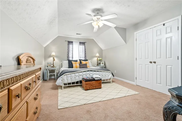 This cozy bedroom features a sloped ceiling and comfortable carpeting for a warm, inviting atmosphere.