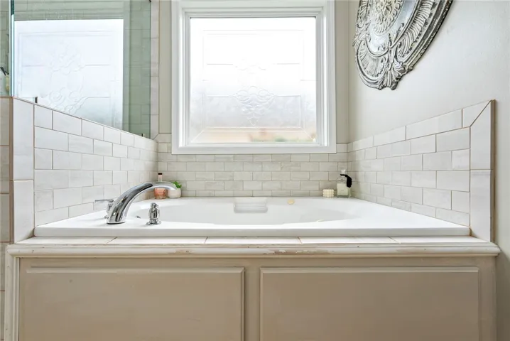 Relax in this inviting soaking tub, complete with elegant tile surround and natural light.