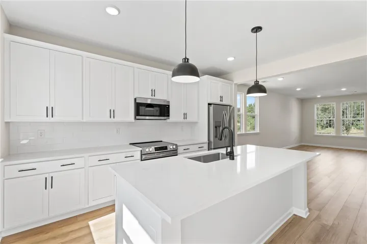 A well-equipped kitchen boasts an expansive island with a sink and modern pendant lighting.