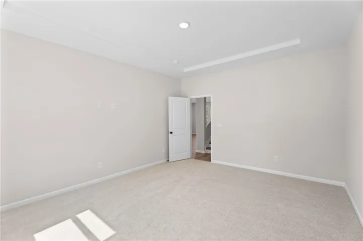 A spacious, naturally illuminated room featuring clean, neutral tones and a chic tray ceiling.