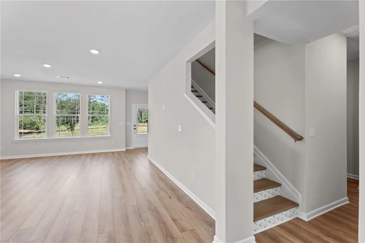 Laminate flooring flows throughout the open-concept living space, leading to a bright entry door and staircase.