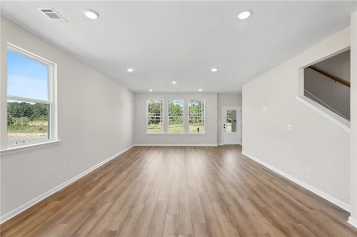Luminous living space featuring durable wood flooring and ample natural illumination.