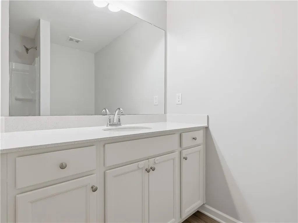 This bright bathroom features a spacious vanity with ample storage and a sleek countertop.