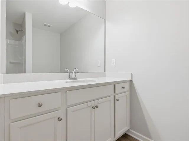 This bright bathroom features a spacious vanity with ample storage and a sleek countertop.