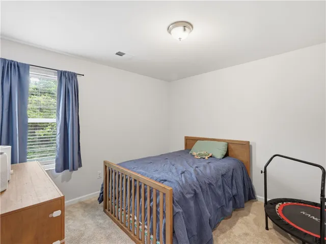 This cozy bedroom features plush carpeting, a single window, and warm, inviting lighting.