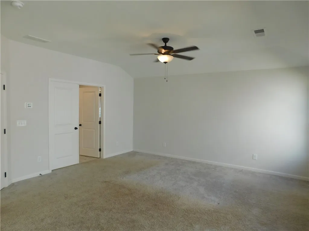 This spacious bedroom offers comfortable carpeting and a ceiling fan for year-round comfort.