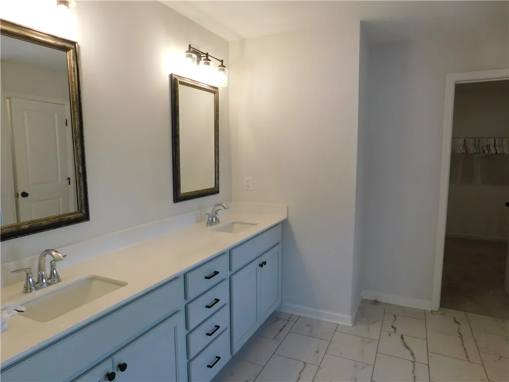 This spacious primary bathroom offers a dual vanity and walk-in closet for ample storage.