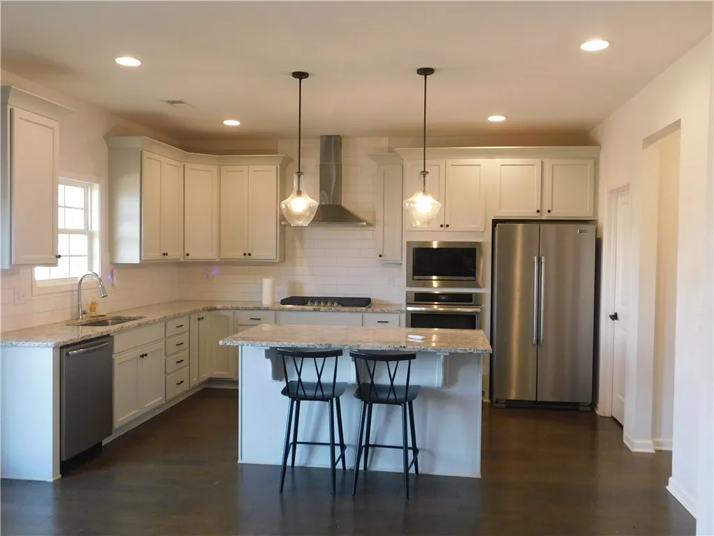 This modern kitchen features elegant countertops, stainless steel appliances, and a convenient island with seating.