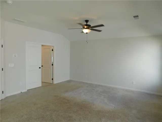 This spacious bedroom offers comfortable carpeting and a ceiling fan for year-round comfort.