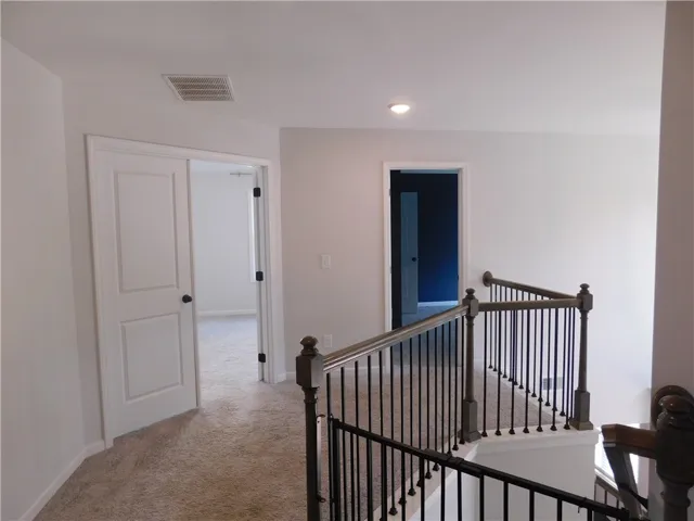 An inviting hallway showcases plush carpeting and elegant railings leading to various rooms.