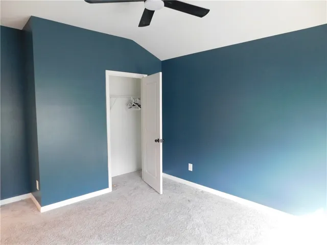 This inviting bedroom features vaulted ceilings and plush carpet flooring.