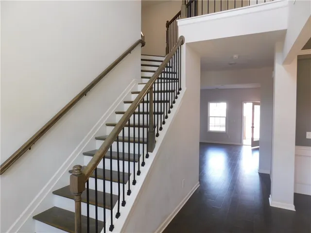 This inviting entryway showcases a grand staircase and gleaming hardwood floors, perfect for a warm welcome.