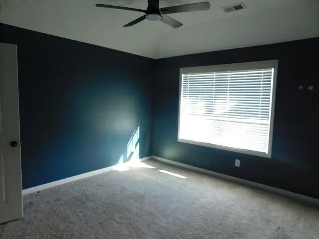 This inviting bedroom features ample natural light and comfortable carpeting, perfect for relaxation.