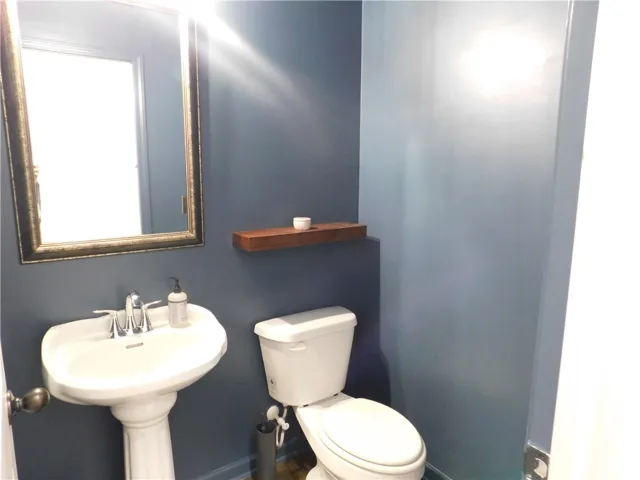 This intimate powder room features a pedestal sink and reflective mirror.