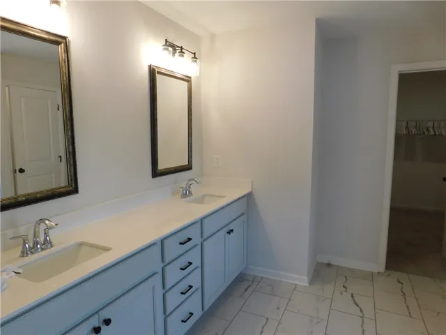 This spacious primary bathroom offers a dual vanity and walk-in closet for ample storage.