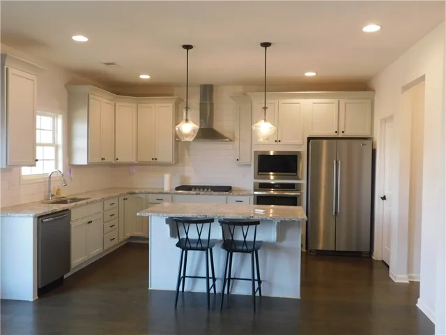 This modern kitchen features elegant countertops, stainless steel appliances, and a convenient island with seating.