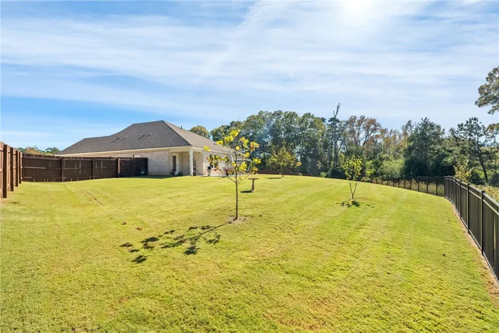 Expansive green lawn extends to a private, fenced yard, offering ample outdoor space and privacy.