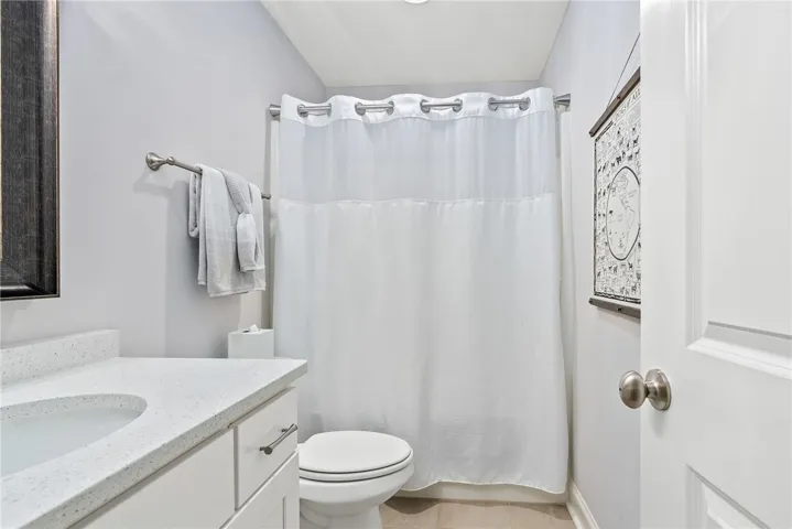 Quartz countertops, a tub/shower combination, and generous space make this bathroom both functional and inviting for family or guests.