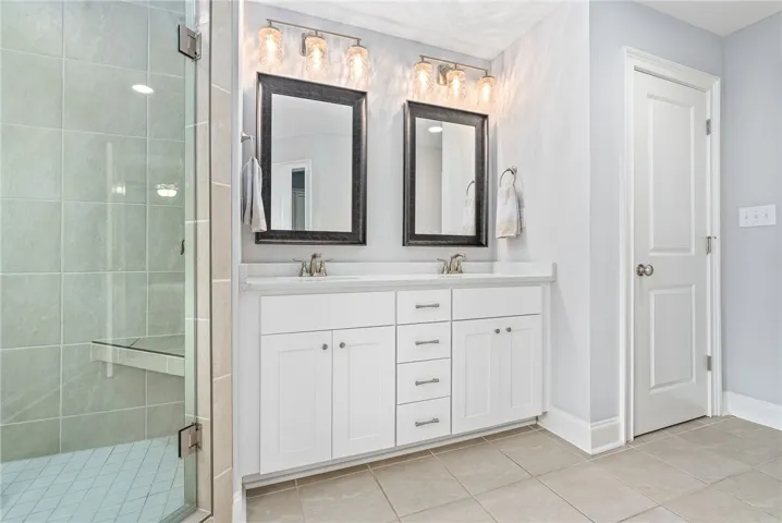 The primary bath features a dual sink vanity, walk-in tile shower, soaking tub, linen closet, water closet, and custom walk-in closet.
