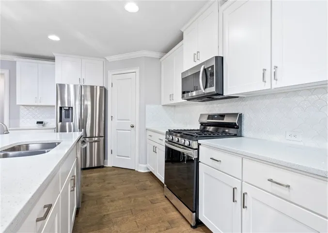 This kitchen checks every box with quartz countertops, a chic backsplash, stainless appliances, a two-bay sink, walk-in pantry, coffee bar, & generous cabinetry.