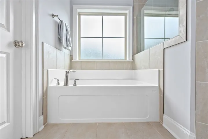 Positioned beneath a window outfitted with privacy glass, the soaking tub enjoys natural light.